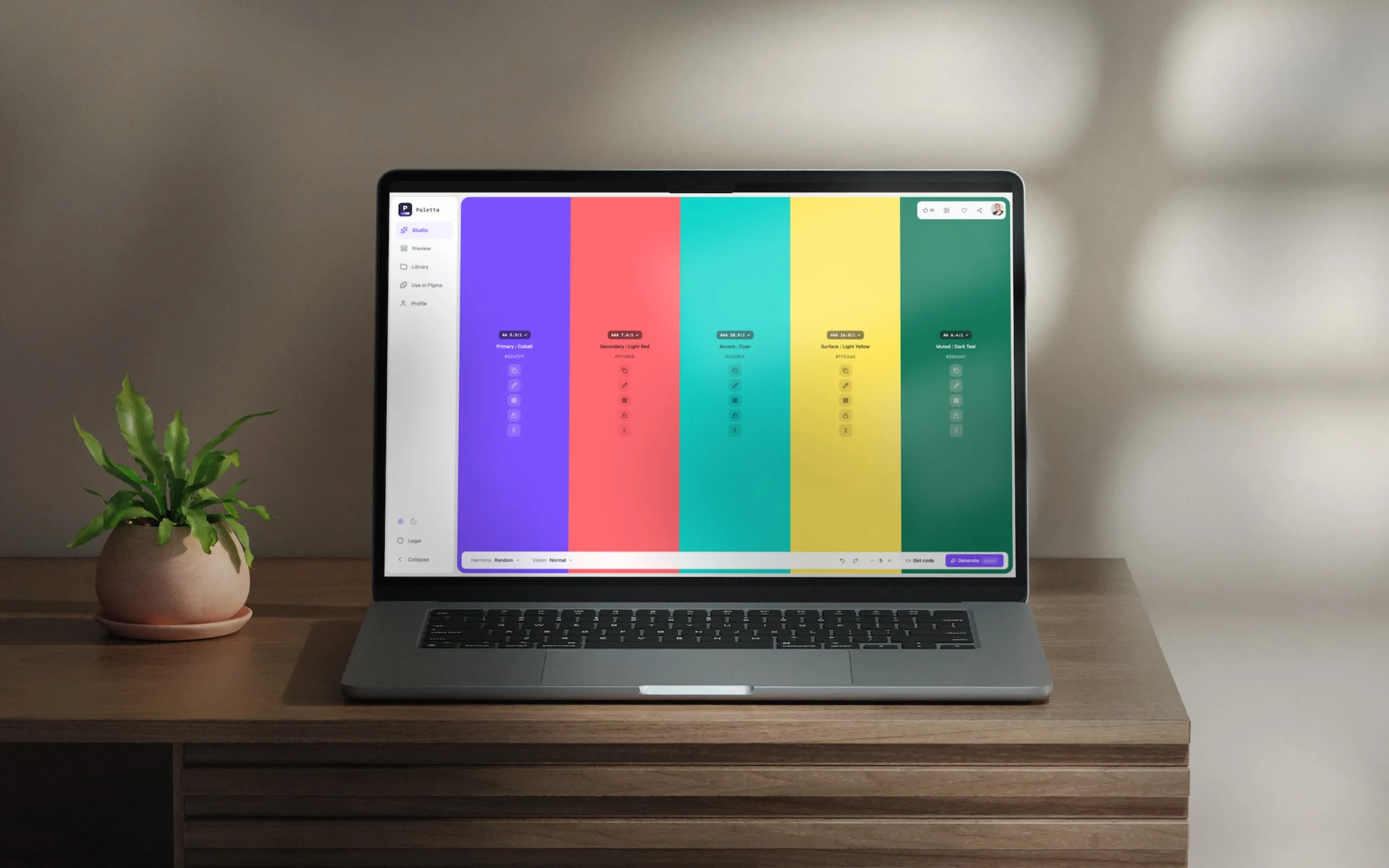 Paletta open on a laptop on a wooden desk beside a plant, showing a generated palette as full-height colour columns.