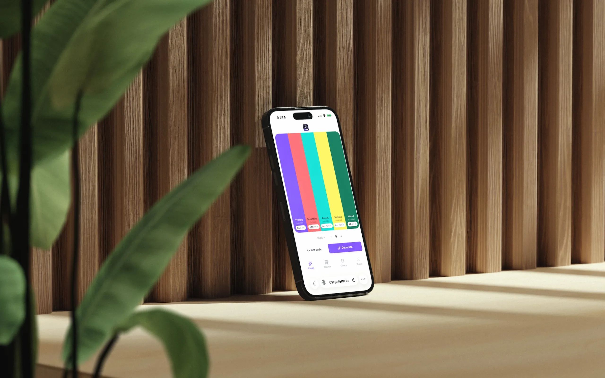 Paletta running on an iPhone against wood slats, the palette rendered as vertical colour bars on the small screen.