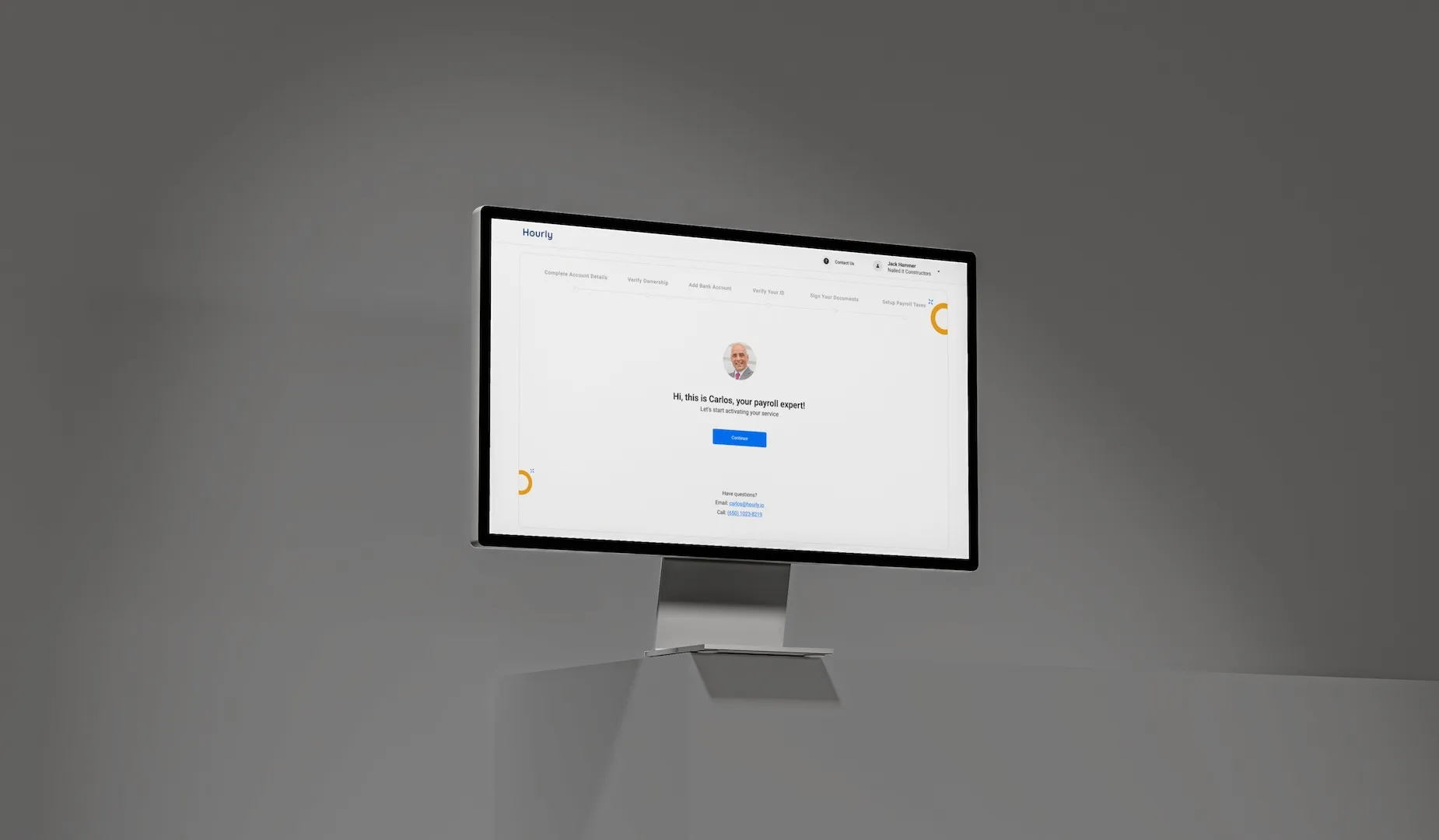 A monitor on a grey studio backdrop showing the Hourly onboarding welcome screen with its six-step progress bar.